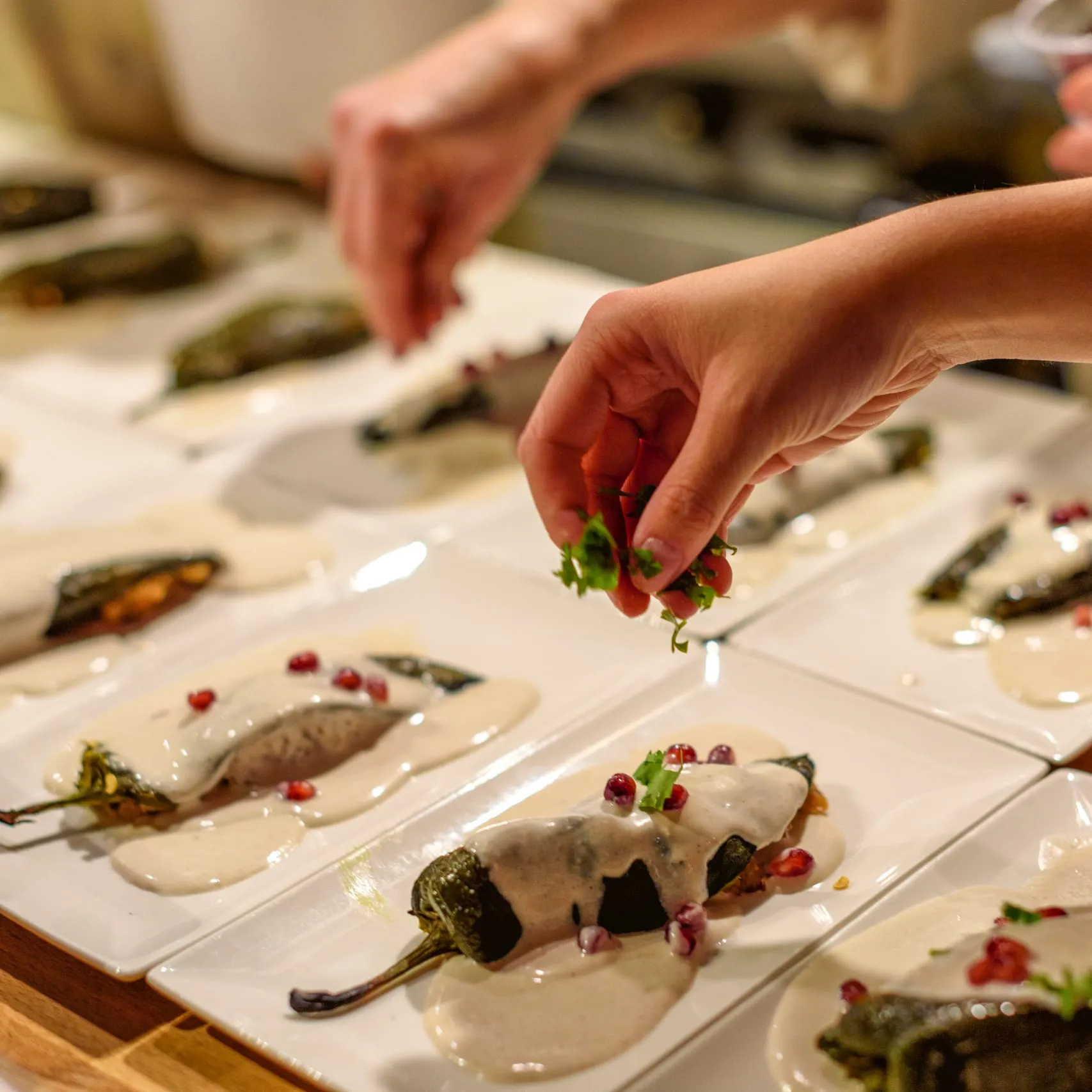 Cilantro scattered over stuffed poblanos finished with crema and pomegranate