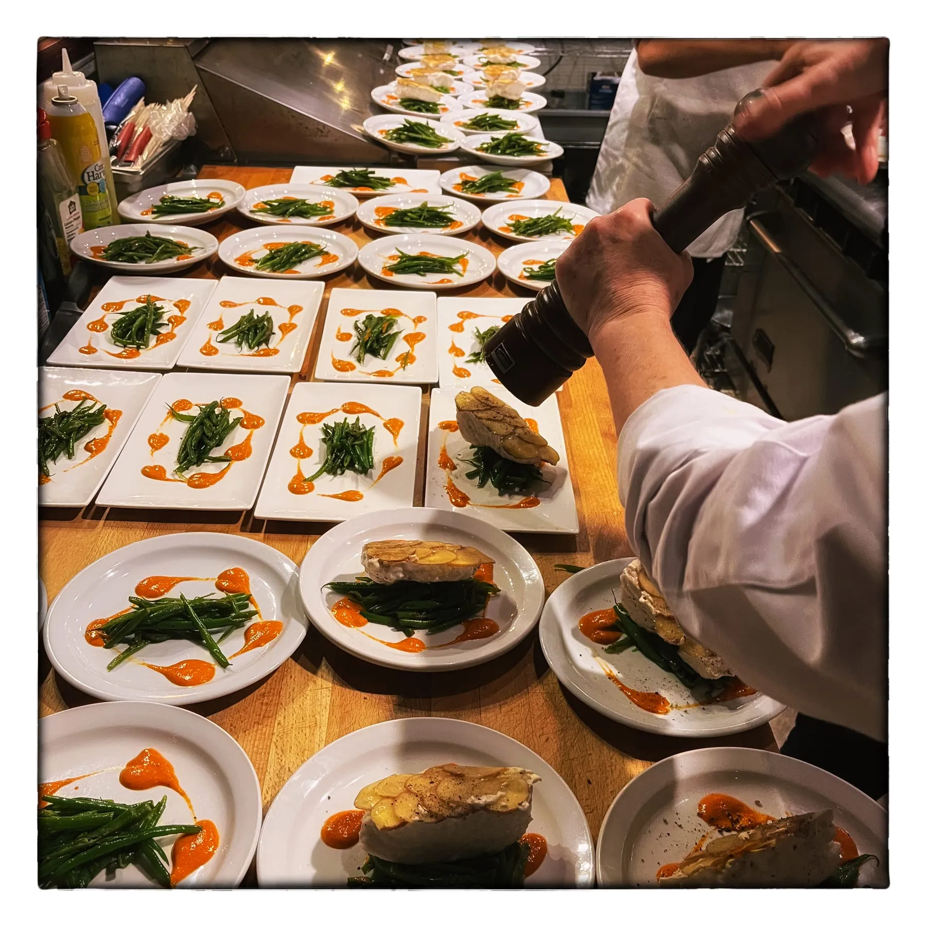 Chef Janet Wait finishing a line of plated courses during service