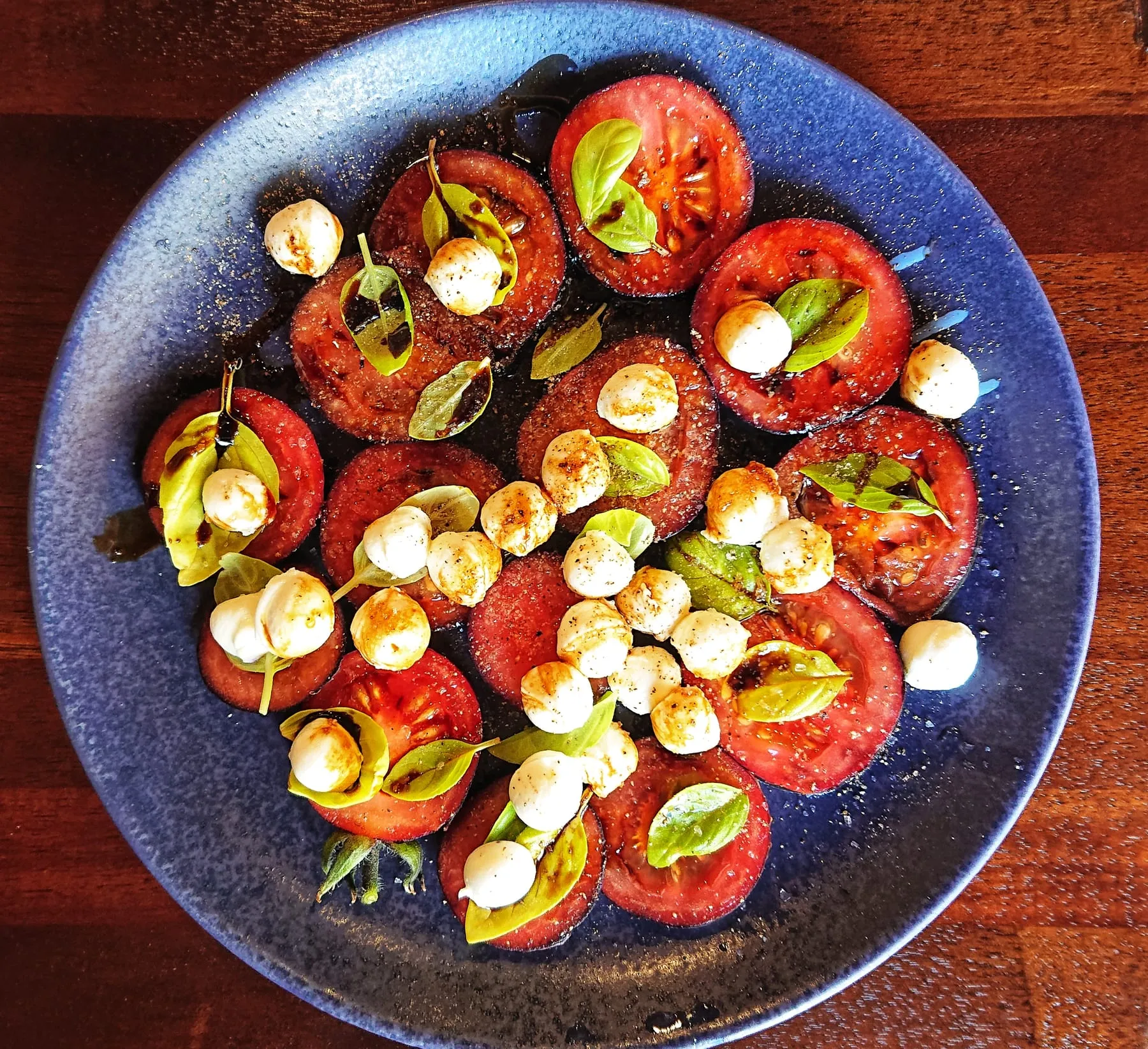 Heirloom tomato and bocconcini salad on a blue plate