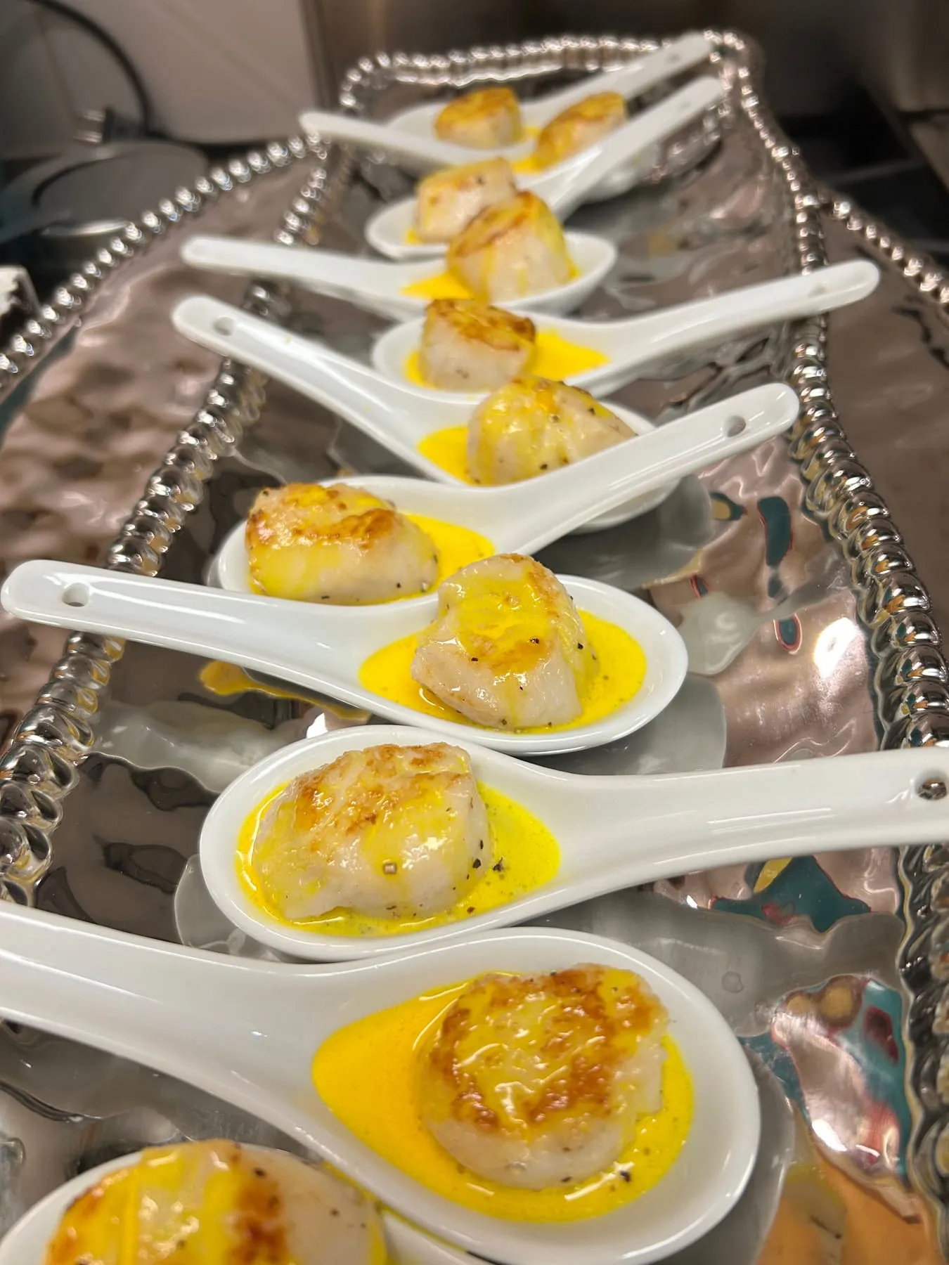 Seared scallops on tasting spoons, plated for a private dinner
