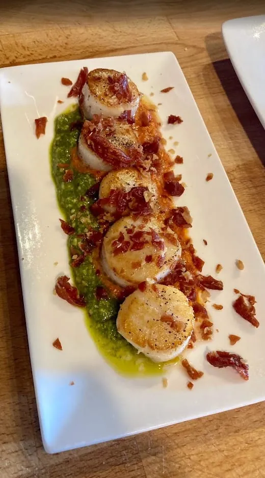 Seared scallops on a herb purée and red pepper sauce, finished with crisp cured ham